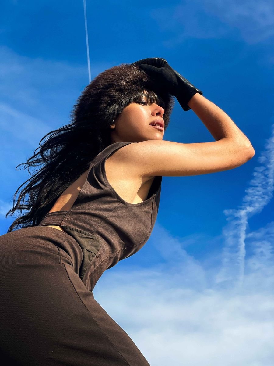 Print: model shielding her eyes against a blue sky