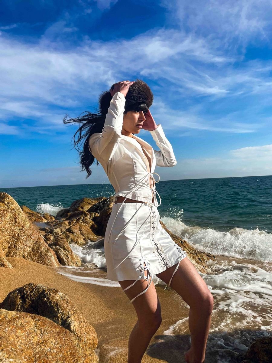 Model in a white suit on a beach with waves behind